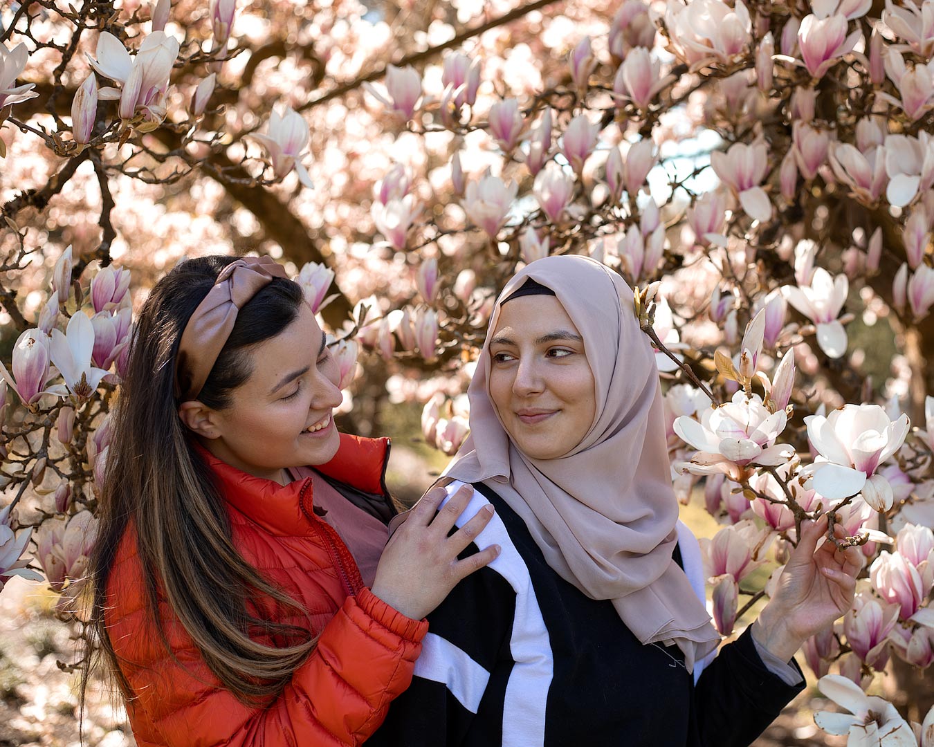 Portrait von zwei Freundinnen zwischen Magnolienblüten