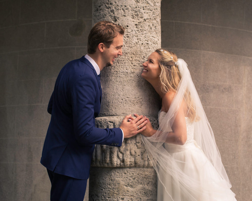 Hochzeit Brautpaar steht an einer Säule und schaut sich an