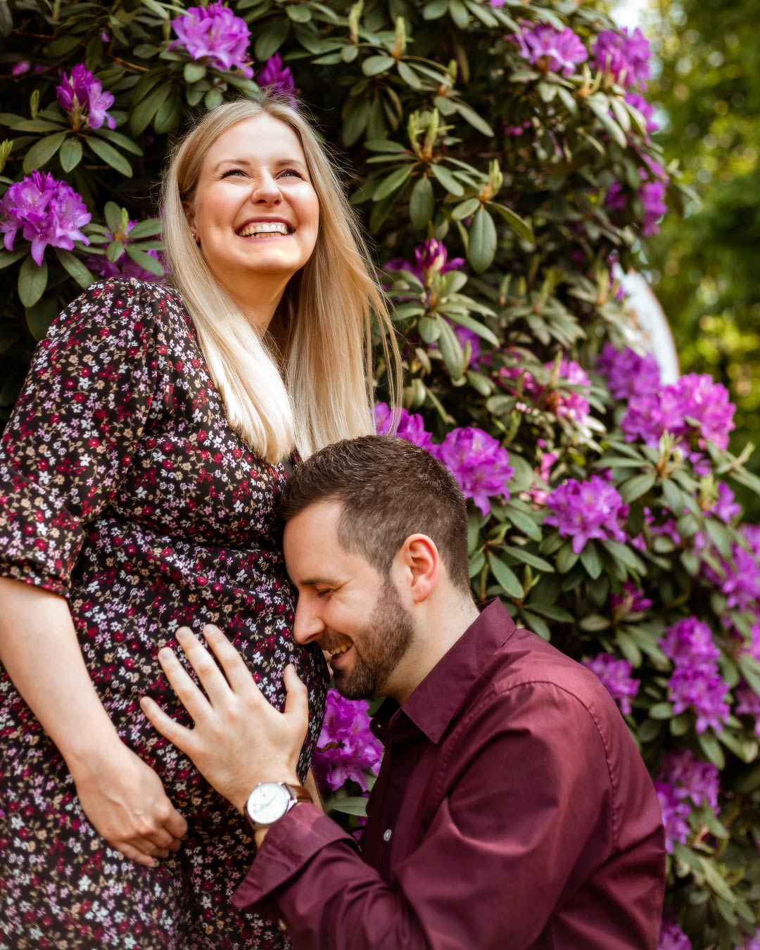 Portrait Paar mit Babybauch vor lila Rhododendron