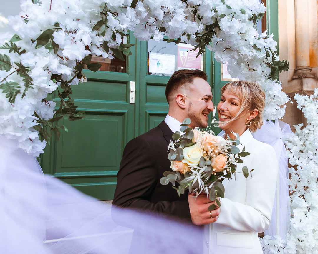 Brautpaar vor grüner Tür mit Schleier