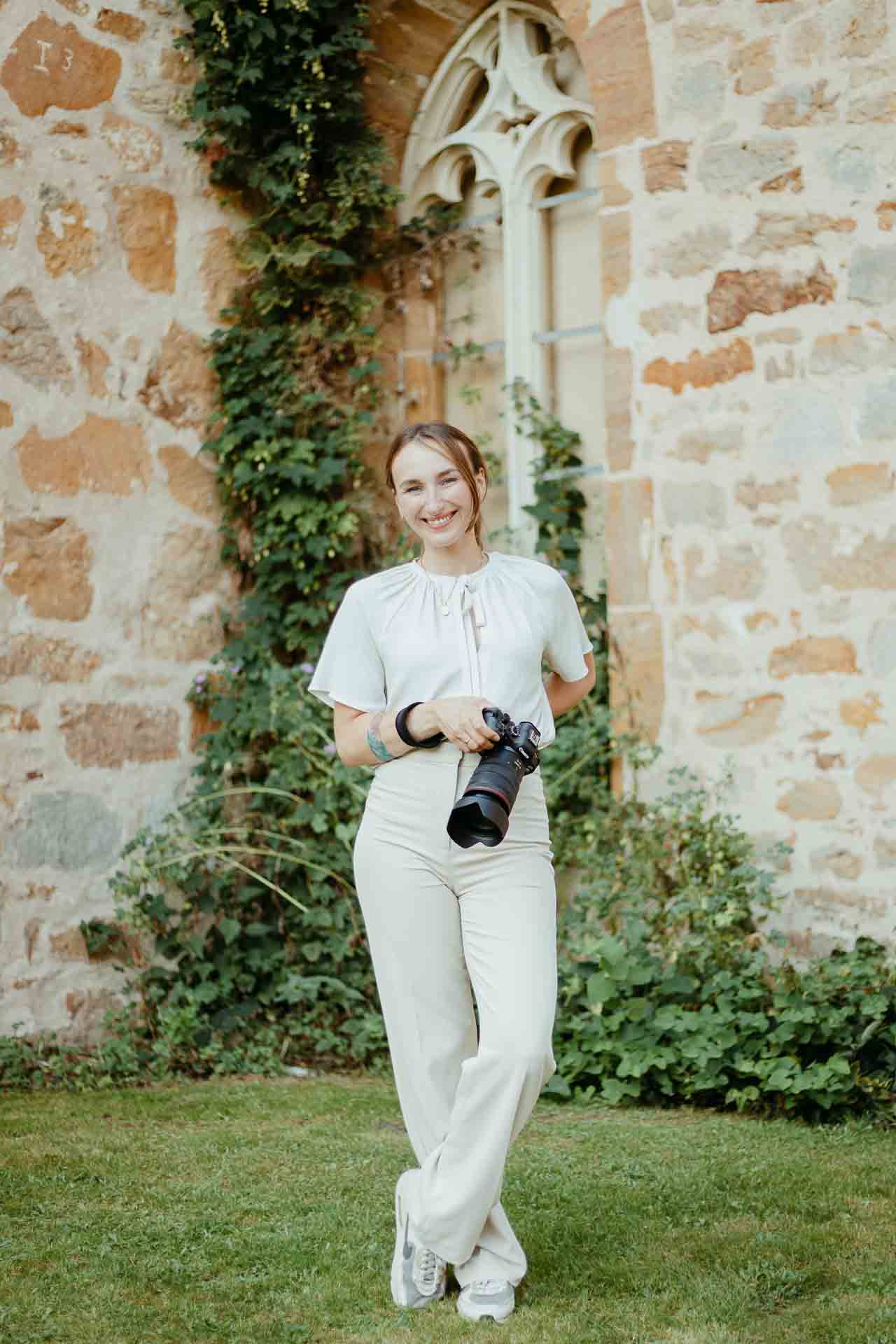 Hochzeitsfotografin Elopementfotograf Karoline Reher steht vor Efeu bewachsenem Kloster Bentlage Münster