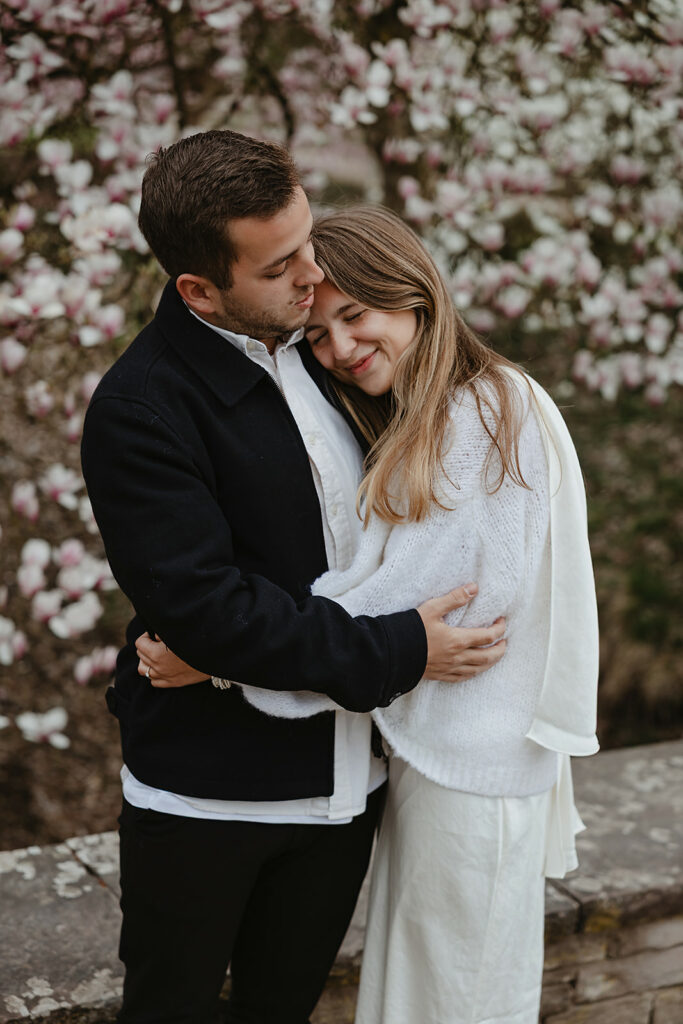 Fotoshooting im Frühling Paar umarmt sich vor einem blühenden Strauch