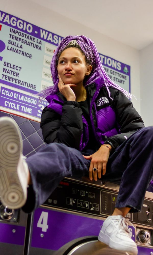 Frau in einem Waschsalon mit lila Jacke von The North Face bei einem Fotoshooting für Social Media