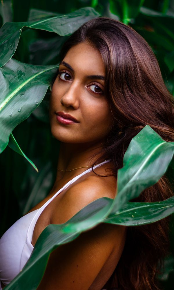Portraitfoto junge Frau umgeben von grünen Blättern