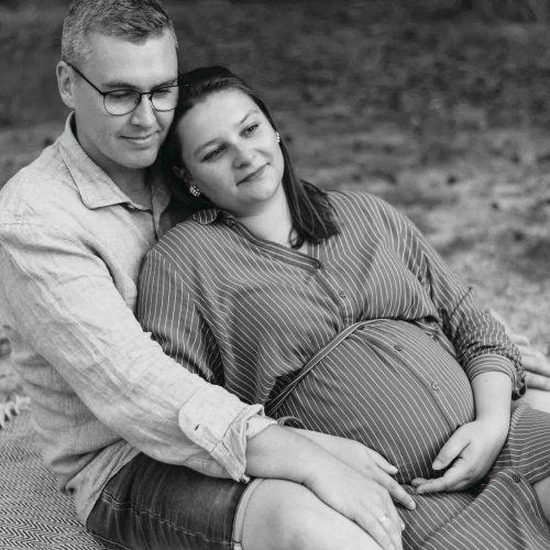 Schwangerschaftsfotos im Wald Schwangere und Mann an einander angelehnt Babybauchfotos