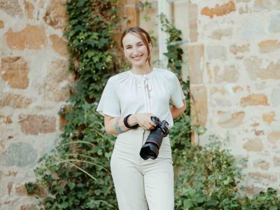Hochzeitsfotografin Elopementfotograf Karoline Reher steht vor Efeu bewachsenem Kloster Bentlage Münster