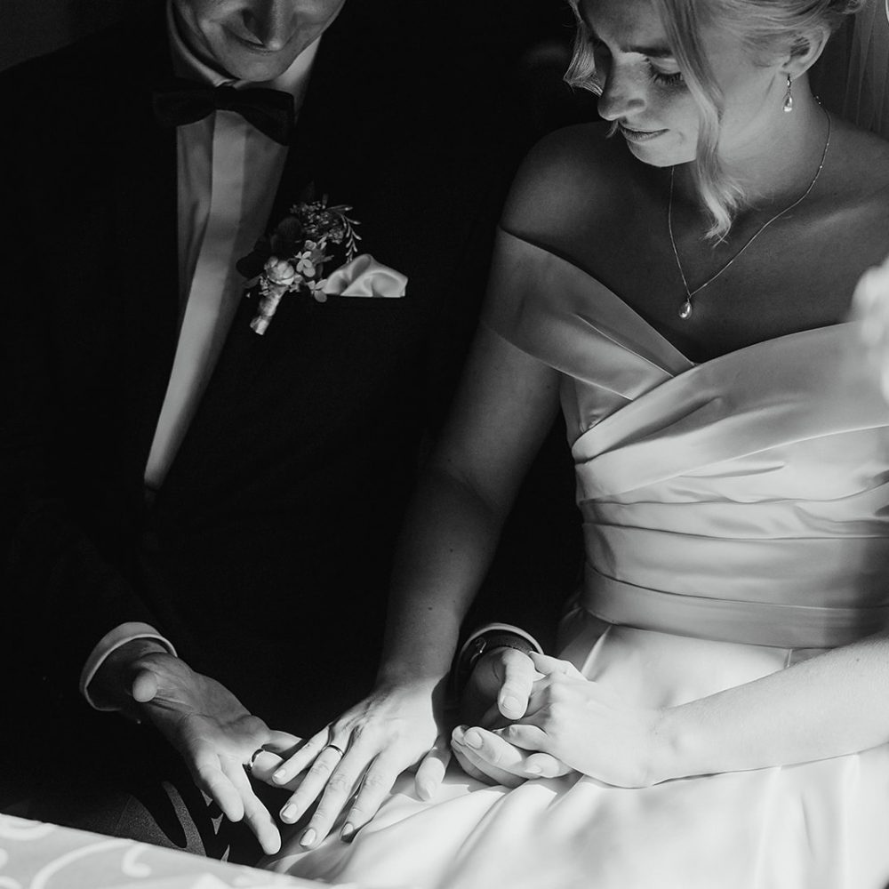 Top Hochzeitsfotograf Brautpaar betrachtet ihre Ringe bei der Trauung intime exklusive Hochzeitsfotografie im Kloster Bentlage Münster Trauung mit eigenen Eheversprechen