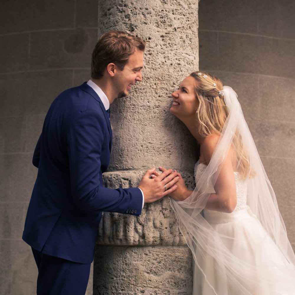 Hochzeit Brautpaar steht an einer Säule und schaut sich an
